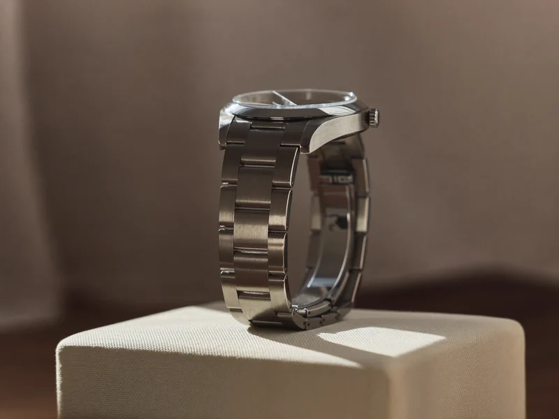 Edelstahluhr mit Gliederarmband, schräg von unten auf einem cremefarbenen Stoffblock fotografiert
